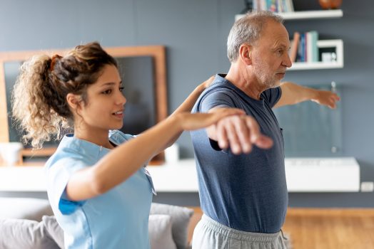 Nurse making a house visit to a senior patient and examining her shoulder - healthcare and medicine concepts